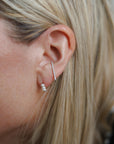 Close up of person wearing 8.6.4 triangle ear cuff in silver with trio of freshwater pearls earring stud.