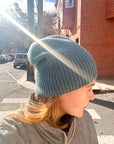 Woman wearing a light blue cashmere beanie on city street.