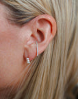 Close up of person wearing 8.6.4 triangle ear cuff in silver with trio of freshwater pearls earring stud.