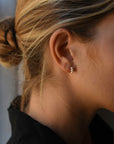 Close up of woman wearing a modern pair or 8.6.4 pearl earrings, featuring a trio of freshwater pearls.