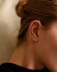 Side view of person wearing 8.6.4 triangle ear cuff in brass.