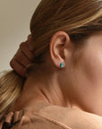 Woman with hair pulled back in a ponytail, showing a turquoise double bead stud earring