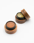 Open Abature lip scrub and serum pots with a wooden lid resting on top