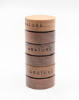 Stack of wooden containers with Abature's lip products, on a white background