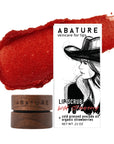 Abature lip scrub with red color swatch and packaging featuring a woman's face.