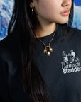 Woman wearing Victorian Revival gold-fill necklace with three carved shell cameos hanging from a gold-fill bar with delicate floral links in between, over a black, graphic tshirt.