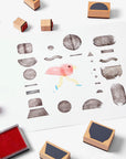 Collection of wooden rubber stamps, stamp pad and children's artwork.