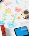 Colorful children's artwork with rubber stamps and ink pad on a white surface