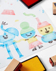 Collection of wooden rubber stamps, stamp pad and children's artwork.