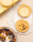 Mini tart shells topped with wildflower sugar beside a glass bowl of the sugar