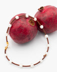 Necklace featuring hand strung pearls spaced out on a leather cord draped on a pomegranate