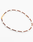 Handmade pearl and leather cord necklace laying flat on a white background
