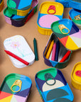 Top Draw tins with pull-tab lids, crayons and a small drawing pad with a child's flower sketch