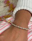 Wrist wearing a braided rainbow cotton friendship bracelet with a wooden bead