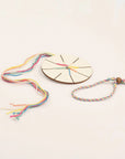 Wooden weaving disc threaded with colorful cotton beside a finished bracelet