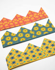 Three paper celebration crowns in orange, teal and mustard floral and star prints