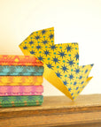 Mustard star-print paper crown standing in front of a stack of patterned crowns