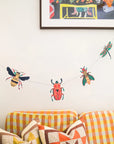 Insect paper garland with beetles, bees and a dragonfly strung above a checkered sofa