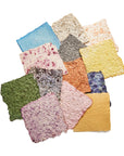 Handmade paper squares in green, pink, gold and gray, flecked with dried herbs and flowers