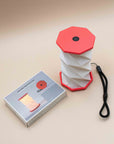 Hexagon twist light with coral top and base popped open beside its box and wrist strap