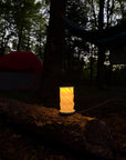 Hexagon twist light glowing on a log at a campsite in the woods