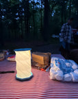Teal hexagon paper lantern light on a striped picnic table at camp with marshmallows