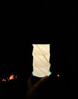 Hand holding the lit Gingko hexagon twist light in the dark beside a campfire