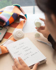 Person writing in a notebook next to a 5-minute sand timer on a desk