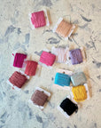 Embroidery floss bobbins in pink, mustard, teal and black from the landscape kit