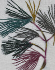 Close-up of the pine boughs stitching in deep green, mustard and dusty plum