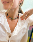 Close-up of a person wearing a colorful beaded necklace and white blouse.