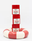 Stack of 3 red and white 'Ouch Balm' stick containers on a white background