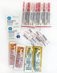 Pocket Aid Kit contents laid out: bandages, alcohol prep pads, ointment and sunscreen packs