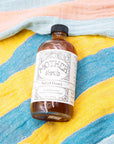Bottle of 'Mother Shrub' Salted Honey on a striped fabric background