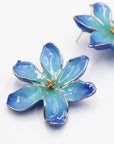 Close-up of Frost Flower porcelain earrings with blue petals outlined in gold