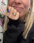 Smiling woman wearing the Nach Bijoux Once Upon a Time ring with a blue bird and black flower