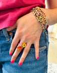 A hand-painted porcelain floral and gold ring worn on a person's hand