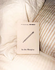 In the Margins career journal with a pencil drawing on the cover, propped on bed pillows