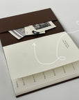Open Off the Grid travel journal showing its back pocket holding tickets and photos