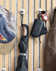 ONO keychain case hanging on a wall hook beside an umbrella and a cap