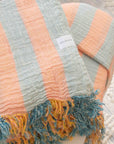 Striped Turkish towel with frayed edges and a brand label