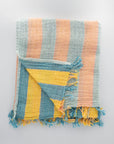 Colorful striped Turkish towel with frayed edges on a light gray background