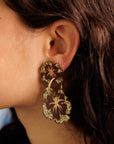 Close-up of an ear wearing a handpainted gold and burgundy floral earring