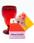 Hilma af Klint playing cards with colorful design and a red glass on a white background