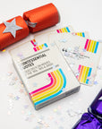 Quintessential Quotes movie quiz deck with rainbow stripes beside an orange cracker