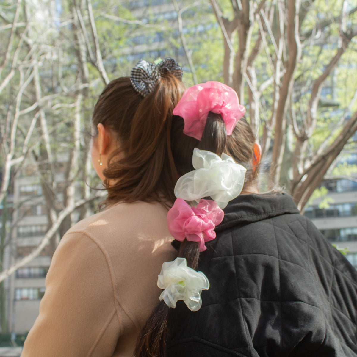 girl wearing pink and white organza "cloud" scrunchies, leaning against another girl in the park