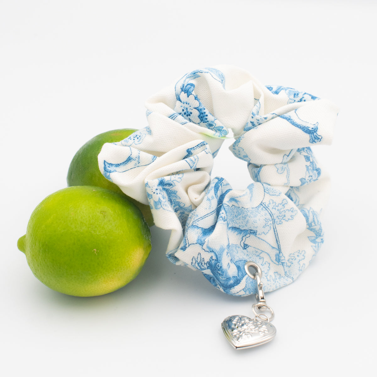 toile scrunchie with silver locket charm next to limes