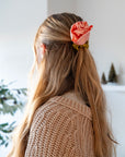 Back of a woman wearing a peach satin rosette scrunchie in a half ponytail with a beige sweater