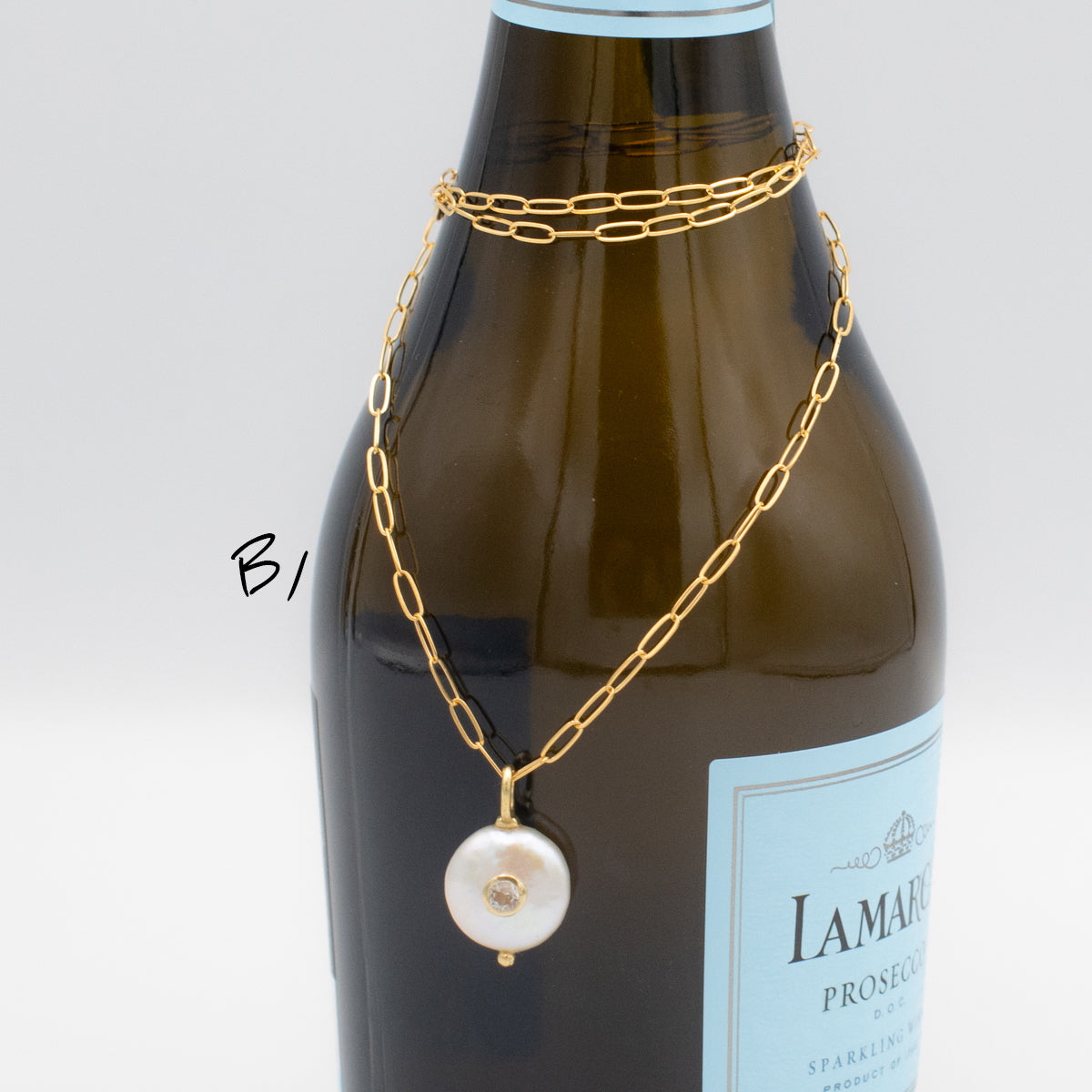 Pearl with set-in white topaz gemstone on a gold paperclip chain necklace