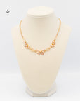 Signed 1940s Van Dell necklace featuring sculptural bows in yellow and rose gold fill, with a 15.5in chain and extender on a jewelry bust.